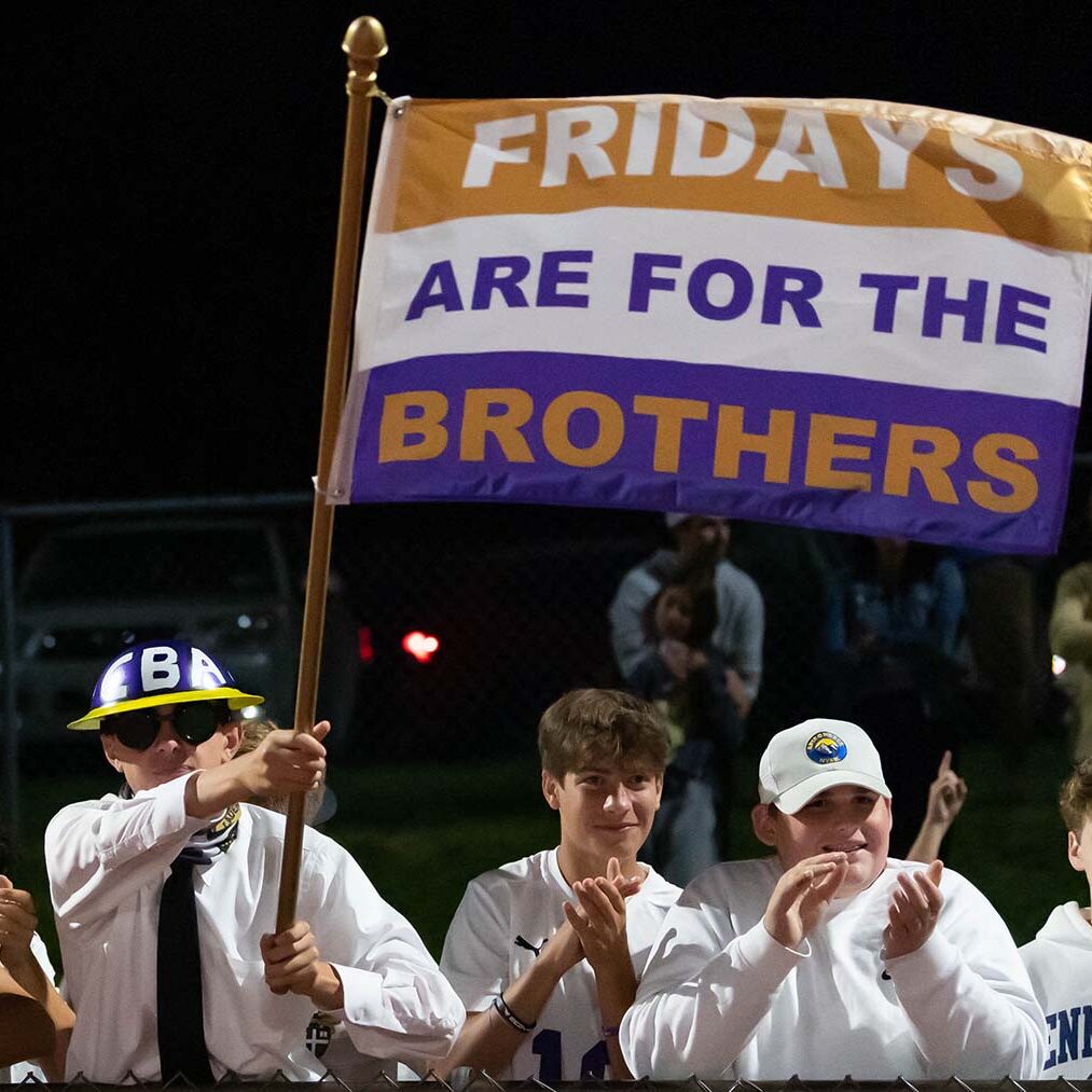 Students at football game waving school flag